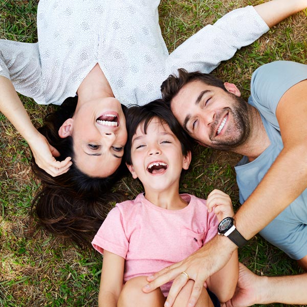 family of three laughing and laying on grass